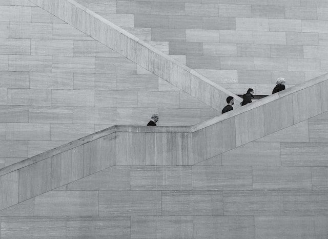 black and white photo of people ascending a gloomy staircase